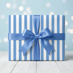 Blue striped wrapping paper with a satin bow for birthdays and baby showers by Wrapped Studios.