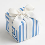 Blue and white striped wrapping paper with a white velvet bow for baby shower gifts, by Wrapped Studios.