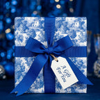 Luxury blue toile wrapping paper with a royal blue ribbon bow and gift tag by Wrapped Studios.