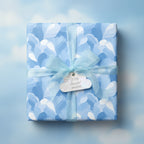 Wrapped gift with blue floral wrapping paper, soft blue ribbon, and cloud-shaped tag reading "With deepest wishes".