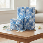 Elegant presents wrapped in blue floral wrapping paper with light blue satin ribbon on a wood table.