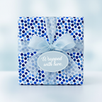 Square gift wrapped in blue polka dot paper, tied with sheer blue ribbon, and a "Wrapped with love" tag.