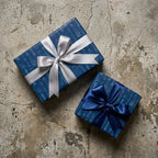 Blue rocket ship wrapping paper with silver and blue satin bows on gift boxes by Wrapped Studios.