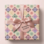 Elegant pastel mandala wrapping paper with a pink satin bow and gift tag by Wrapped Studios.