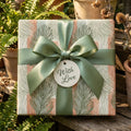 Luxury botanical wrapping paper with sage green leaves, terracotta stripes, and satin bow by Wrapped Studios.