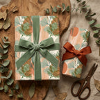 Botanical wrapping paper with sage green and terracotta leaf patterns, tied with velvet ribbon by Wrapped Studios.