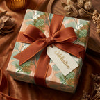 Luxury botanical wrapping paper with sage green leaves and rust ribbon by Wrapped Studios.