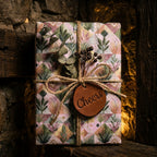 Luxury botanical wrapping paper with rustic twine and a leather Cheers tag by Wrapped Studios.