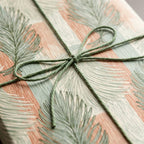 Terracotta and green palm leaf wrapping paper tied with a sage twine bow by Wrapped Studios.