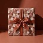 Luxury terracotta floral wrapping paper with a rust satin bow on a gift box by Wrapped Studios.