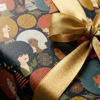 Luxury holiday wrapping paper with illustrated Black women and a gold bow by Wrapped Studios.