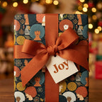 Afrocentric Black women Christmas gift wrap with orange ribbon and Joy tag by Wrapped Studios.