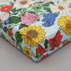 Square gift wrapped in light blue floral wrapping paper with colorful flower pattern.