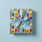 Square gift wrapped in light blue floral wrapping paper with a satin ribbon and bow.