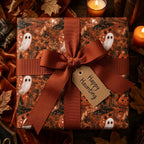 Spooky Halloween wrapping paper with ghosts and pumpkins, tied with a rust bow by Wrapped Studios.