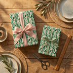 Pink and green cactus wrapping paper with satin ribbons on a rustic table by Wrapped Studios.
