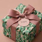 Cactus birthday wrapping paper with a dusty pink bow and Enjoy tag by Wrapped Studios.