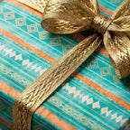 Teal and orange geometric wrapping paper with a metallic gold ribbon bow by Wrapped Studios.