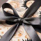 Celestial vintage sun and moon wrapping paper with a dark grey satin bow, by Wrapped Studios.