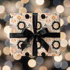 Celestial wrapping paper with a vintage sun and moon pattern and black bow by Wrapped Studios.