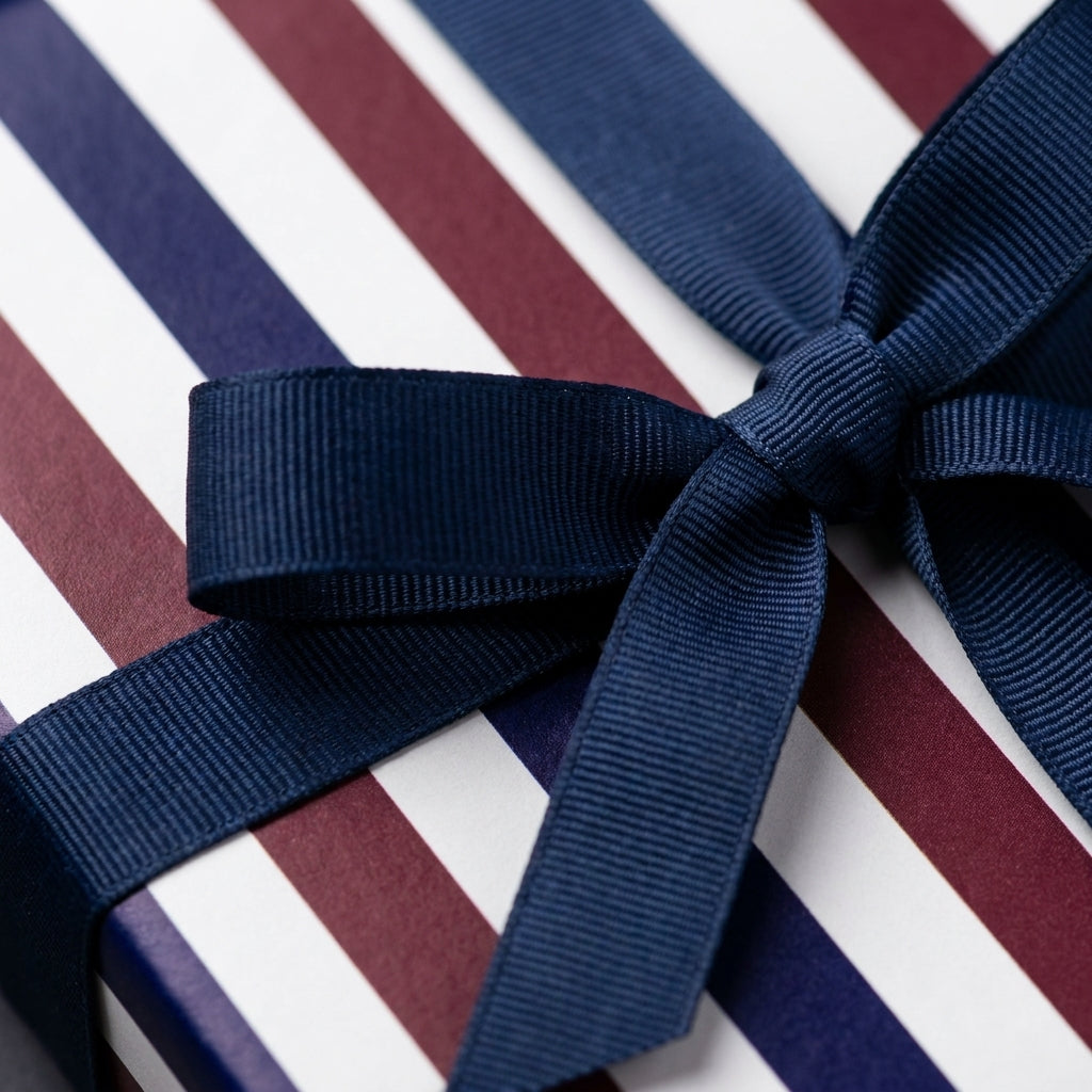 Luxury navy and burgundy striped wrapping paper with a blue ribbon bow from Wrapped Studios.