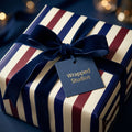 Luxury navy and burgundy striped gift wrap with a velvet bow, featuring a Wrapped Studios tag.