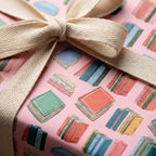 Pink book lover wrapping paper with illustrated books and a cotton ribbon by Wrapped Studios.