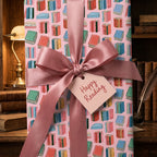 Book lover wrapping paper with a pink satin bow in a library by Wrapped Studios.