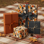 Fall themed gift wrap with leaf print, solid box tied with velvet ribbon, outdoors on plaid blanket with acorns.