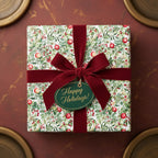 Square gift wrapped in floral Christmas wrapping paper with a red velvet bow and "Happy Holidays!" tag.