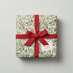 Square gift wrapped in festive floral Christmas gift wrap with a red ribbon bow.