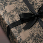 Elegant luxury gift wrap with a black floral and bird pattern tied with a black ribbon.