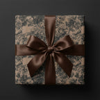 Elegant floral wrapping paper with a satin brown ribbon bow, ideal for luxury gift wrap. Wrapped Studios.