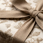 Vintage botanical wrapping paper with a rustic beige herringbone ribbon bow by Wrapped Studios.