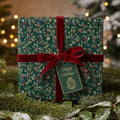 Elegant Christmas gift wrap with dark green floral pattern, red velvet ribbon, and "Happy Holidays!" tag.