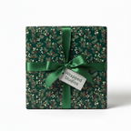 Square gift wrapped in green floral Christmas wrapping paper, tied with a satin bow.