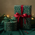 Dark green Christmas gift wrap with floral pattern and satin bows on presents of different shapes.