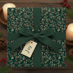 Elegant Christmas gift with dark green floral wrapping paper, ribbon bow, and a "Joy" tag.