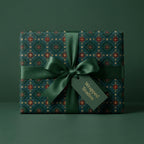 Luxury Christmas gift wrap with green and gold vintage pattern, satin ribbon bow, and Wrapped Studios tag.