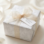 Elegant white floral wrapping paper with a cream ribbon and gift tag by Wrapped Studios.