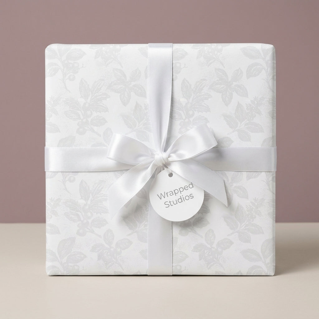 White floral wrapping paper with satin ribbon and gift tag by Wrapped Studios, ideal for elegant wedding gifts.