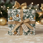 Elegant Christmas wrapping paper featuring a festive botanical pattern with golden ornaments and a gold ribbon, perfect for luxury holiday gifts.