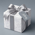 Elegant white floral wrapping paper with a silver satin bow on a gift box, by Wrapped Studios.