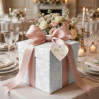 Elegant floral wrapping paper with pink ribbon on wedding gift box at reception table by Wrapped Studios.