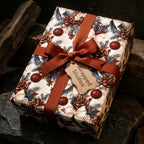 Rustic Christmas gift wrap with a pinecone pattern and red ribbon on a holiday gift box by Wrapped Studios.