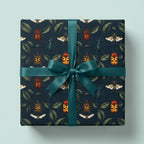Square gift wrapped in beetle-themed wrapping paper with a teal ribbon.