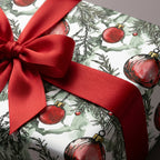 Close-up of a Christmas gift wrapped in ornament patterned paper with a red satin bow.