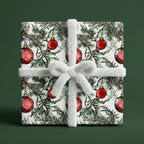 Christmas gift wrap with a red ornaments and pine branch pattern, tied with fluffy white ribbon.
