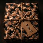 Luxury black and bronze botanical gift wrap by Wrapped Studios, featuring a rustic Cheers tag.