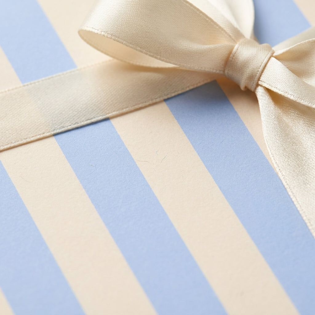 Blue and cream striped wrapping paper with an elegant cream satin bow by Wrapped Studios.
